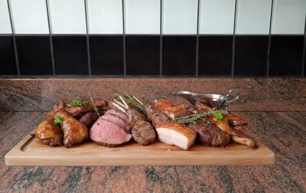 Assortiment de viandes r&ocirc;ties et grill&eacute;es sur planche en bois, avec herbes fra&icirc;ches et sauce.