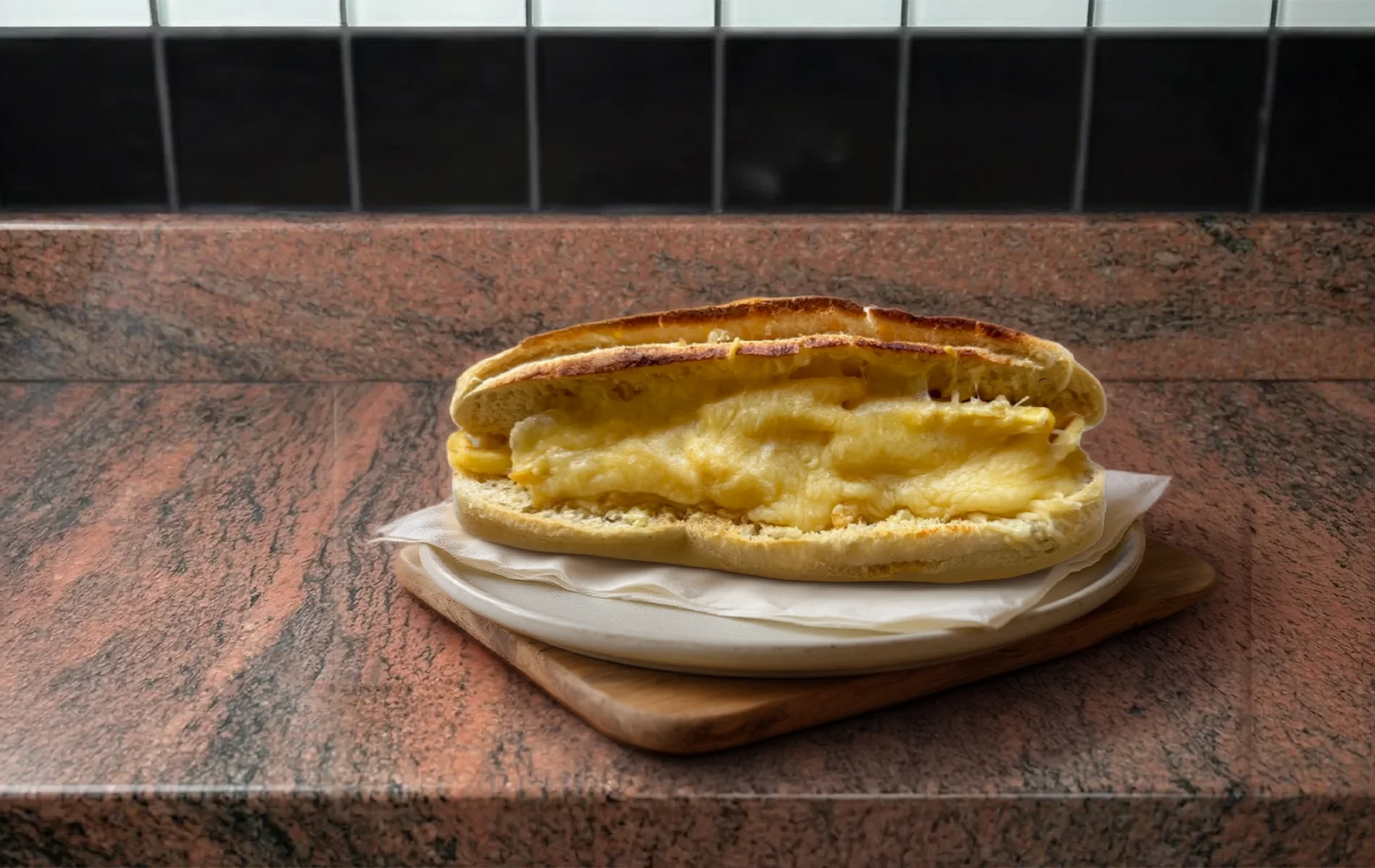 Sandwich r&eacute;unionnais gratin&eacute; au fromage fondant, pr&eacute;sent&eacute; sur une assiette