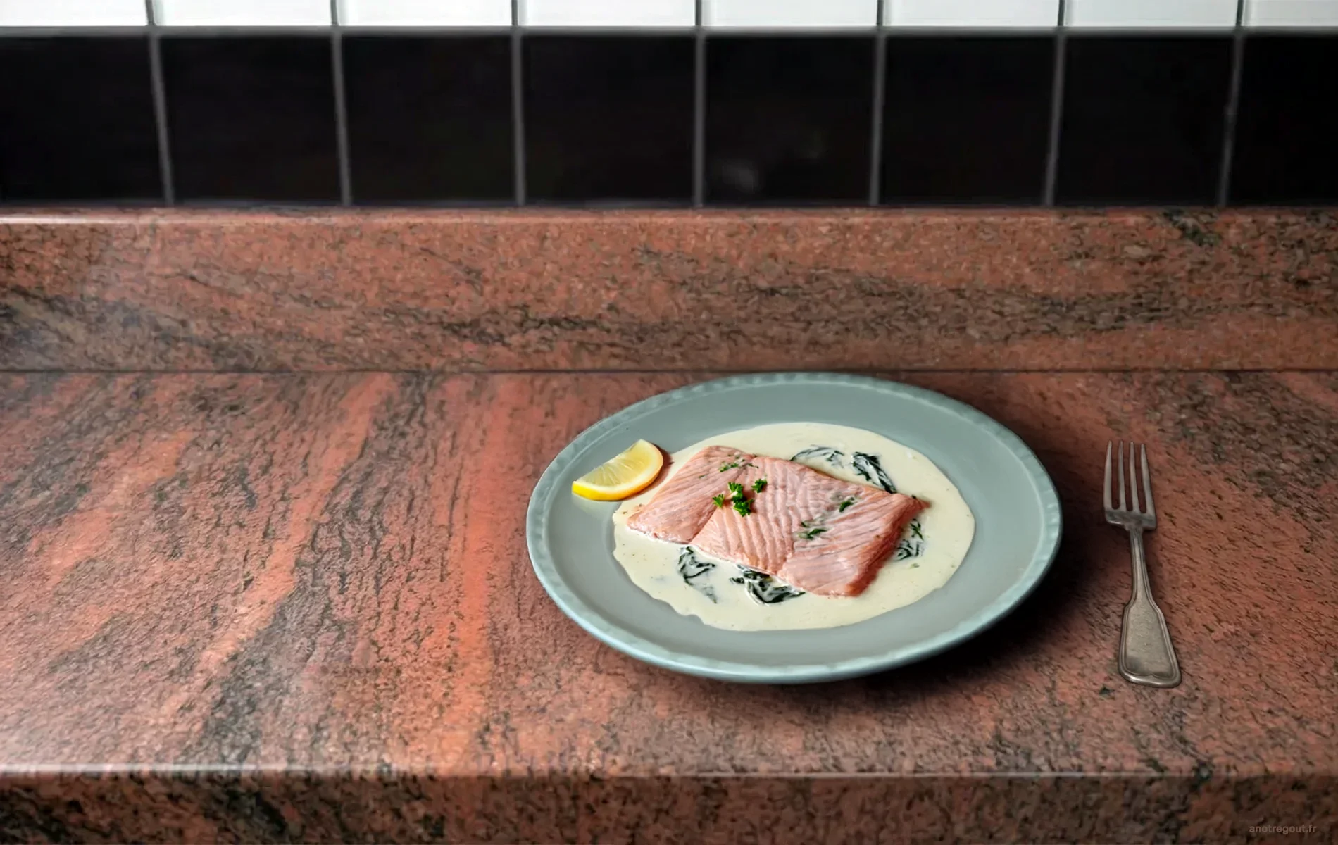 Escalope de saumon à l’oseille avec sauce crémeuse légèrement verte, servie dans une assiette blanche sur un plan de travail en granit..