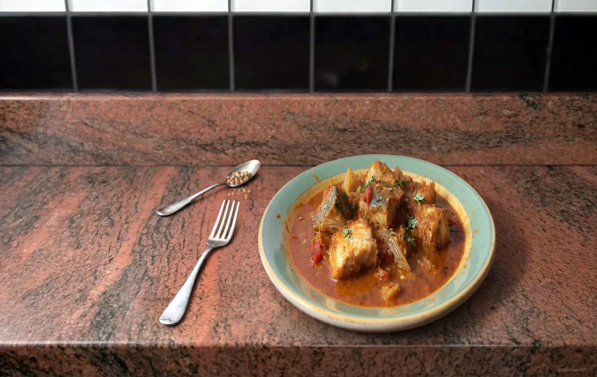 Poisson massal&eacute; en sauce &eacute;pic&eacute;e dans une assiette verte, cuill&egrave;re d&rsquo;&eacute;pices et fourchette &agrave; c&ocirc;t&eacute;