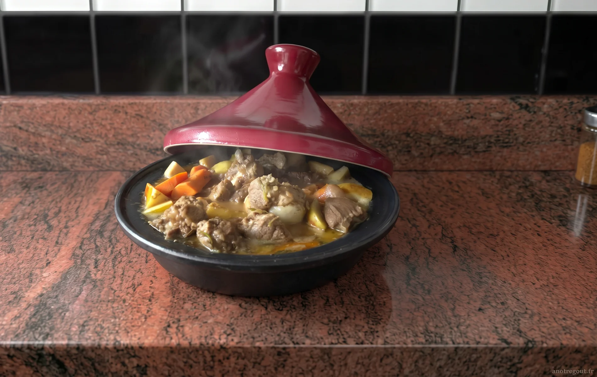 Tajine d&rsquo;agneau fumant avec morceaux de viande, carottes, pommes de terre et sauce mijot&eacute;e, servi dans un plat noir &agrave; couvercle rouge sur un plan de travail en granit