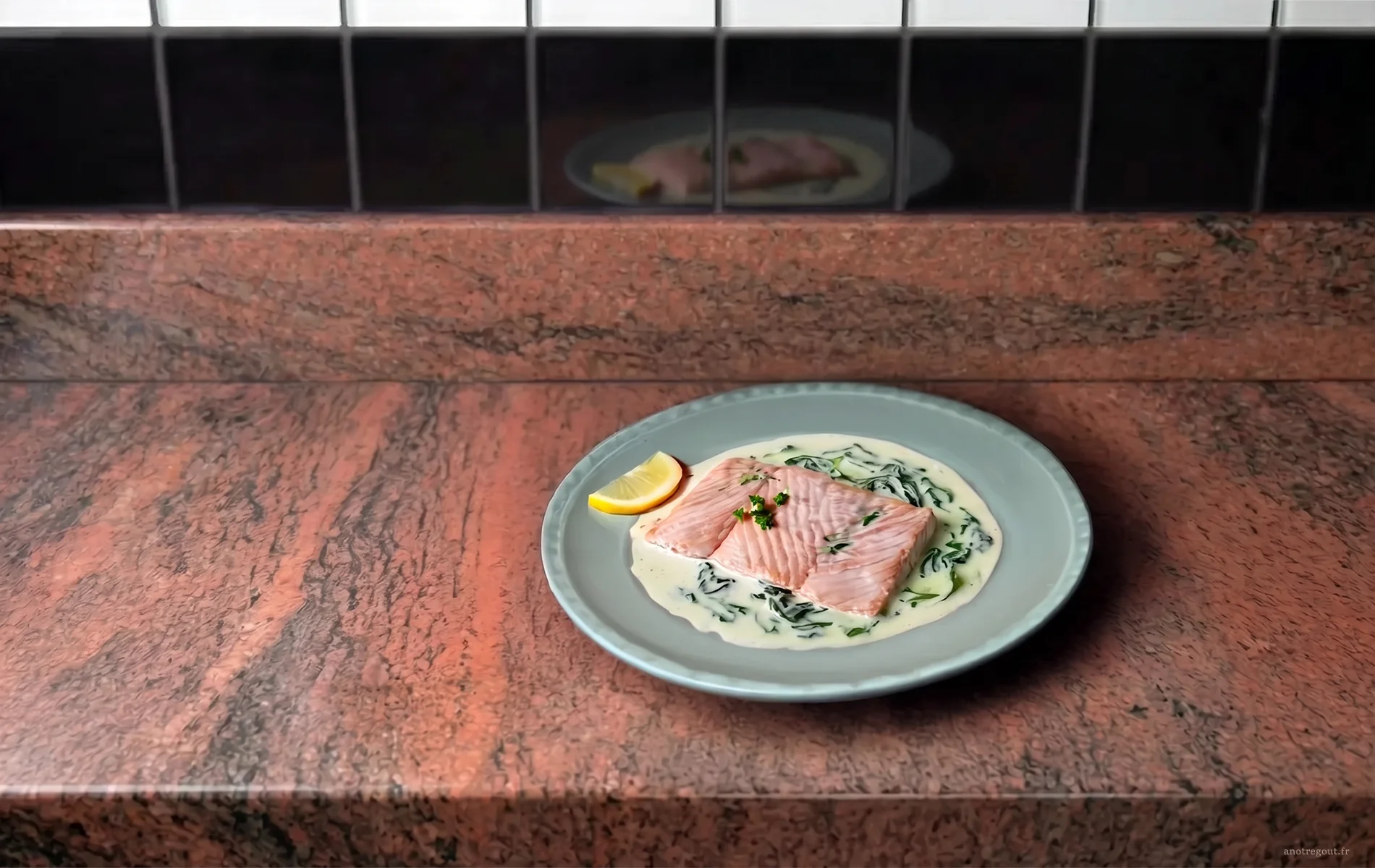 Escalope de saumon servie sur une sauce cr&eacute;meuse &agrave; l&rsquo;oseille dans une assiette grise.